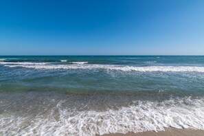 A beach with clear blue water and waves.