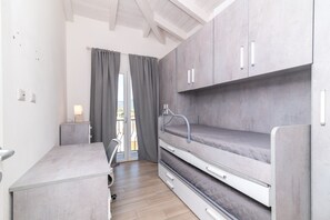 Une petite pièce comprenant un lit superposé, un petit bureau et une chaise.