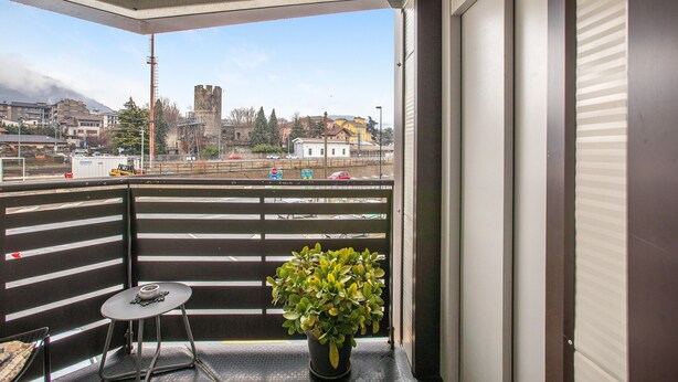 Ein Balkon mit einem Blumentopf, einem kleinen Tisch und Blick auf eine Burg in der Ferne.