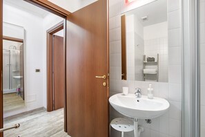 A bathroom with a white sink, a mirror, and a shower area.