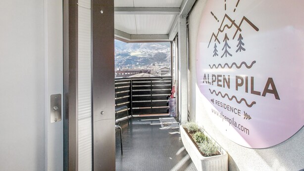 L’entrée d’un hôtel avec vue sur les montagnes et un panneau indiquant « Alpen Pila ».