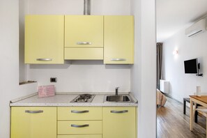 A compact kitchen with a sink, stove, and yellow cabinets.