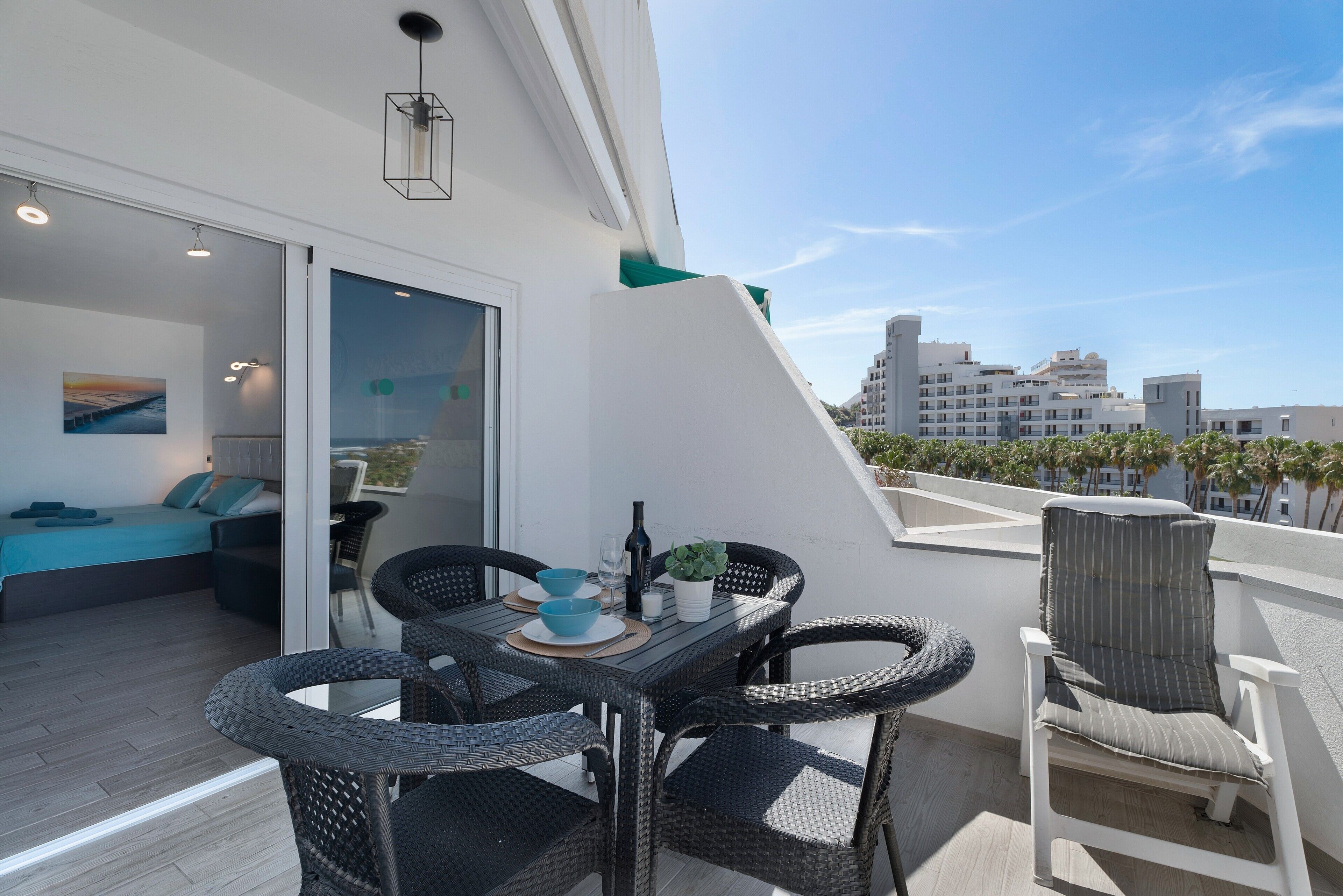 Un balcon agrémenté de meubles en osier, d’une table à manger et offrant une vue sur le paysage urbain.