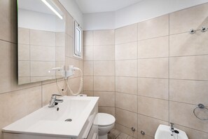 Une salle de bain moderne avec un lavabo blanc, des toilettes et un espace douche.