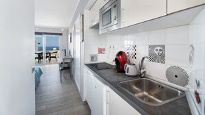 A modern kitchen with white cabinets, a stainless steel sink, and a microwave. - Vacation Studio 'Las Flores 407' with Sea View, Shared Pool and Wi-Fi (Costa Adeje)