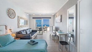A modern hotel room with a bed, a sofa, a desk, and a view of the sea. - Vacation Studio 'Las Flores 407' with Sea View, Shared Pool and Wi-Fi (Costa Adeje)