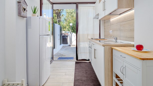 A modern kitchen with white cabinets, a wooden countertop, and a red apple on the sink. - Vacation Home "Sea Wave House" with Private Garden and Wi-Fi (San Teodoro)