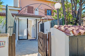 A narrow pathway leading to a building with a tiled roof, a wooden gate, and a lamp post.