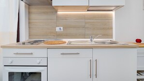 A modern kitchen with a built-in oven, stainless steel sink, and wooden backsplash. - Vacation Home "Sea Wave House" with Private Garden and Wi-Fi (San Teodoro)