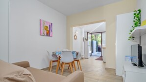 A modern living room with a dining area, a TV on a stand, and a plant on the wall. - Vacation Home "Sea Wave House" with Private Garden and Wi-Fi (San Teodoro)