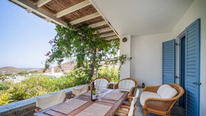 Une table en bois avec des chaises, un canapé en osier et une vue sur le paysage.