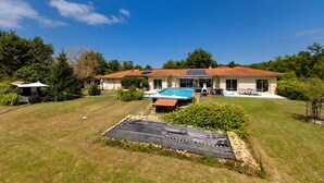 A house with a swimming pool, a tennis court, and a large garden.