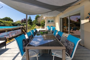 An outdoor dining area with a table and chairs, a pool, and a covered patio.