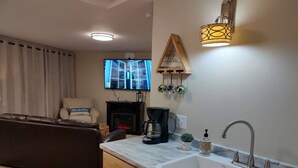 A modern living room with a fireplace, a sofa, a coffee table, and a TV. - Cozy Harborside Condo, Florence (Florence)