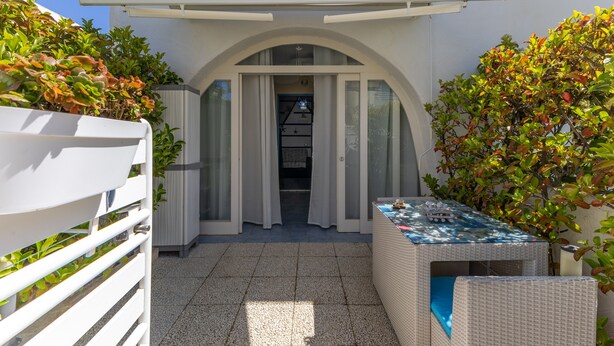 A covered outdoor area with a table, a white fence, and a door leading to a building. - Holiday Apartment "Home Borgo Rio Favara" with Private Terrace & Wi-Fi (Ispica)