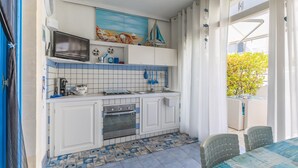 A kitchen with white cabinets, a microwave, a stove, and a sink. There is a tiled backsplash with a nautical theme. - Holiday Apartment "Home Borgo Rio Favara" with Private Terrace & Wi-Fi (Ispica)