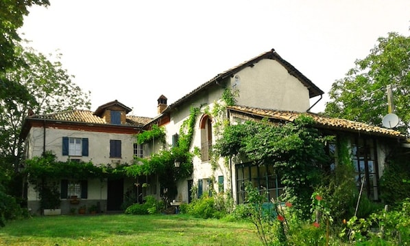 A two-story house with a tiled roof, a garden, and a satellite dish.