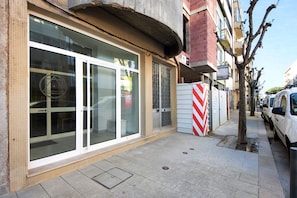 A building with large glass windows, a tiled facade, and a parked car on the sidewalk.