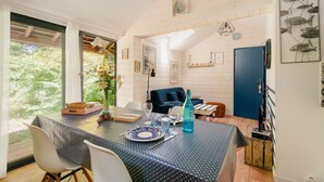 A dining area with a table set for two, a blue patterned tablecloth, and a blue bottle. - Cottage 'Gîte La Marinière' with Private Terrace and Private Garden (Plurien)