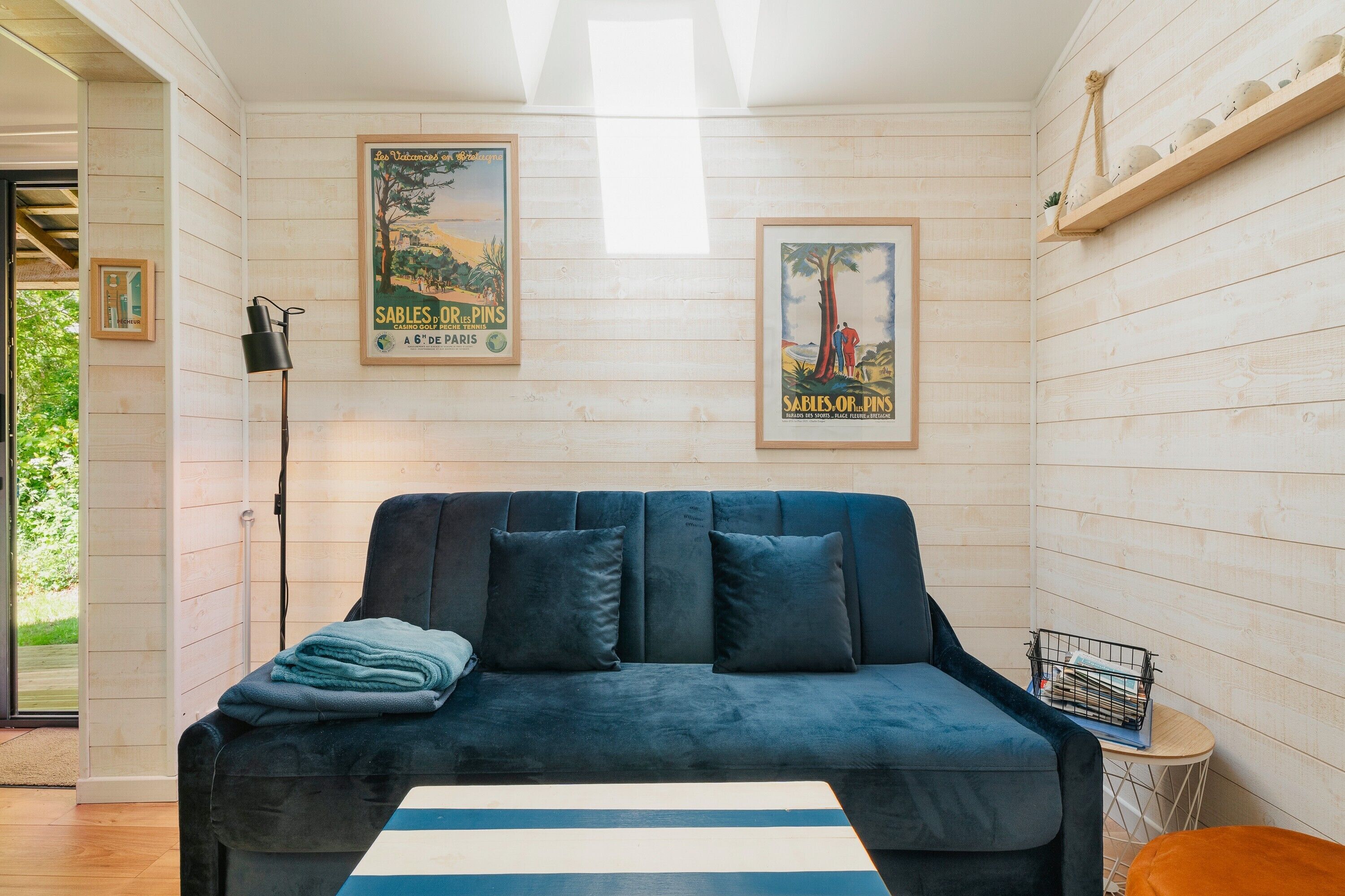 Ein gemütliches Zimmer mit einem dunkelblauen Sofa, einem Streifen Teppich und zwei Vintage-Postern an den Wänden.