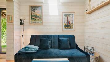 Ein gemütliches Zimmer mit einem dunkelblauen Sofa, einem Streifen Teppich und zwei Vintage-Postern an den Wänden.