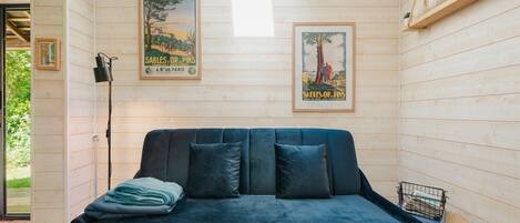 Ein gemütliches Zimmer mit einem dunkelblauen Sofa, einem Streifen Teppich und zwei Vintage-Postern an den Wänden.