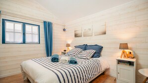 A neatly arranged bedroom with a bed, bedside tables, a lamp, and a small cabinet. - Cottage 'Gîte La Marinière' with Private Terrace and Private Garden (Plurien)