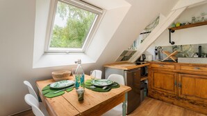 Una cocina con mesa, sillas, una ventana y un armario de madera.