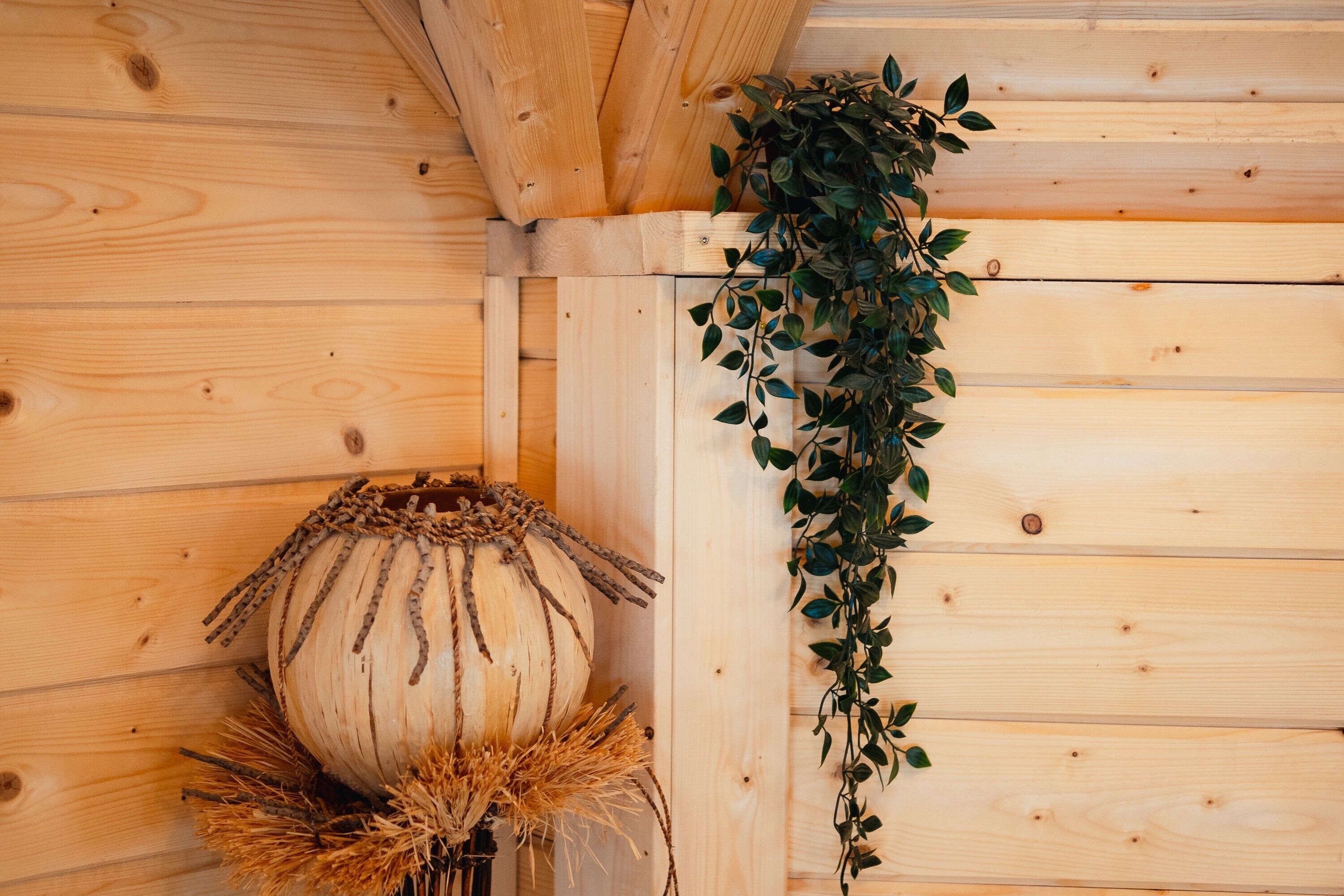 Un mur en bois orné d’une plante suspendue et d’un vase décoratif.