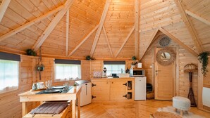 Ein Holzblockbau-Innenraum mit Essbereich, Küchenzeile und einer großen Holztür mit Uhr.