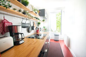 Une cuisine moderne avec des étagères en bois, une machine à café et un tapis rouge sur le sol.
