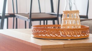 A dining table with chairs, a glass vase, and a woven tray.