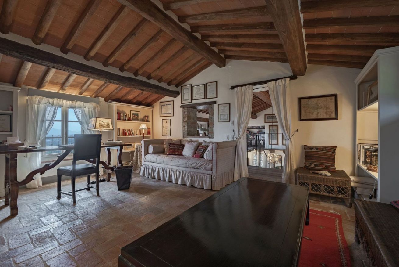 A rustic room with exposed wooden beams, a wooden table, a sofa, and a red rug.