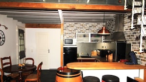 Een keuken met een bakstenen muur, een houten eettafel en een bargedeelte met krukken.