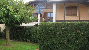 Un edificio de dos plantas con fachada marrón y beige, un diseño geométrico azul en el segundo piso y una valla de madera al frente.