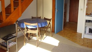 Un comedor con una mesa redonda, sillas y un televisor sobre un mueble.