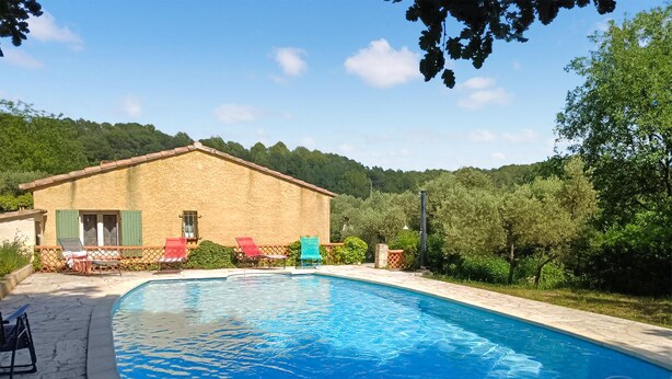 A pool area with lounge chairs and a building with a sloped roof.