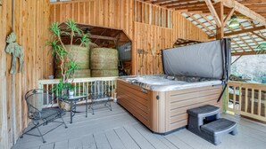 Una terraza de madera con un jacuzzi, fardos de heno y una planta en maceta.