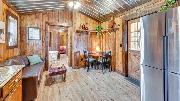 Un interior rústico de madera con comedor, refrigerador y ventilador de techo.