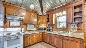 Una cocina con armarios de madera, estufa, microondas y un lavamanos.