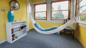 A room with yellow walls, a hammock, a bookshelf, and a window with a view. - The Kings Throne Inn and Guest House (Toledo)
