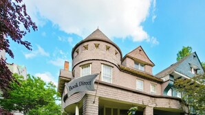 A two-story building with a turret, a porch, and a sign reading 'Book Direct.' - The Kings Throne Inn and Guest House (Toledo)