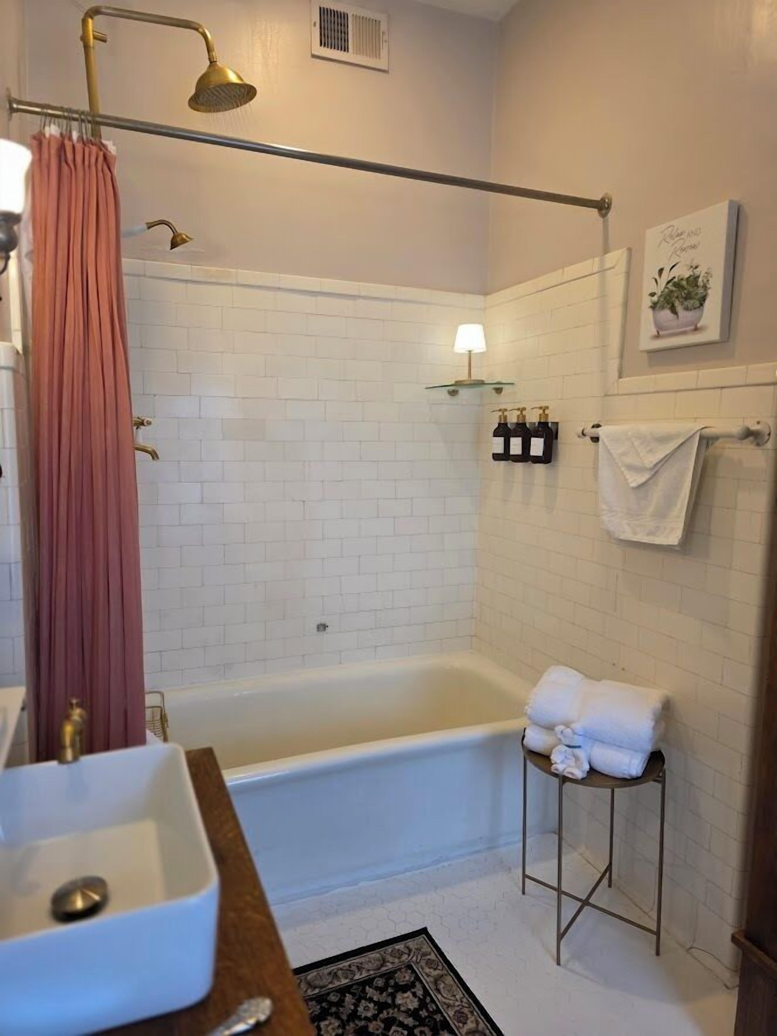 A bathroom with a bathtub, a shower, a sink, and a towel rack.