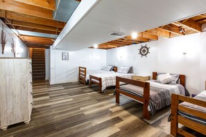 A bedroom with three wooden beds, a white wardrobe, and a wooden ceiling with exposed beams.
