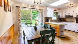 A dining area with a wooden table and chairs, a potted plant, and a view of the outdoors. - New Spacious Warren Dunes Beach & Winery Retreat w/Hot Tub & Pool Table (Bridgman)