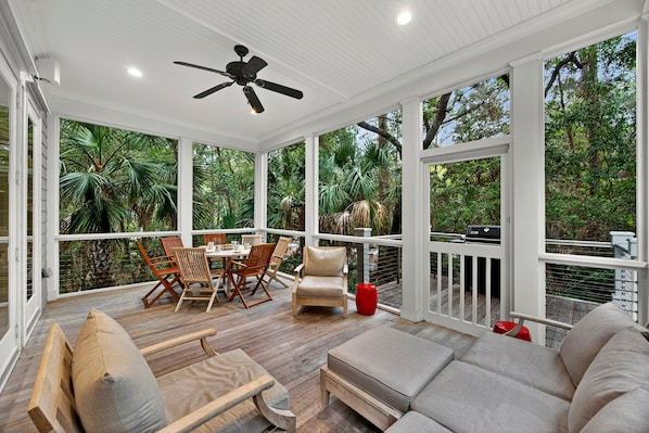 A covered outdoor area with a ceiling fan, wooden furniture, and a view of lush greenery. - Serene & Private Kiawah Retreat with Private Pool (Kiawah Island)