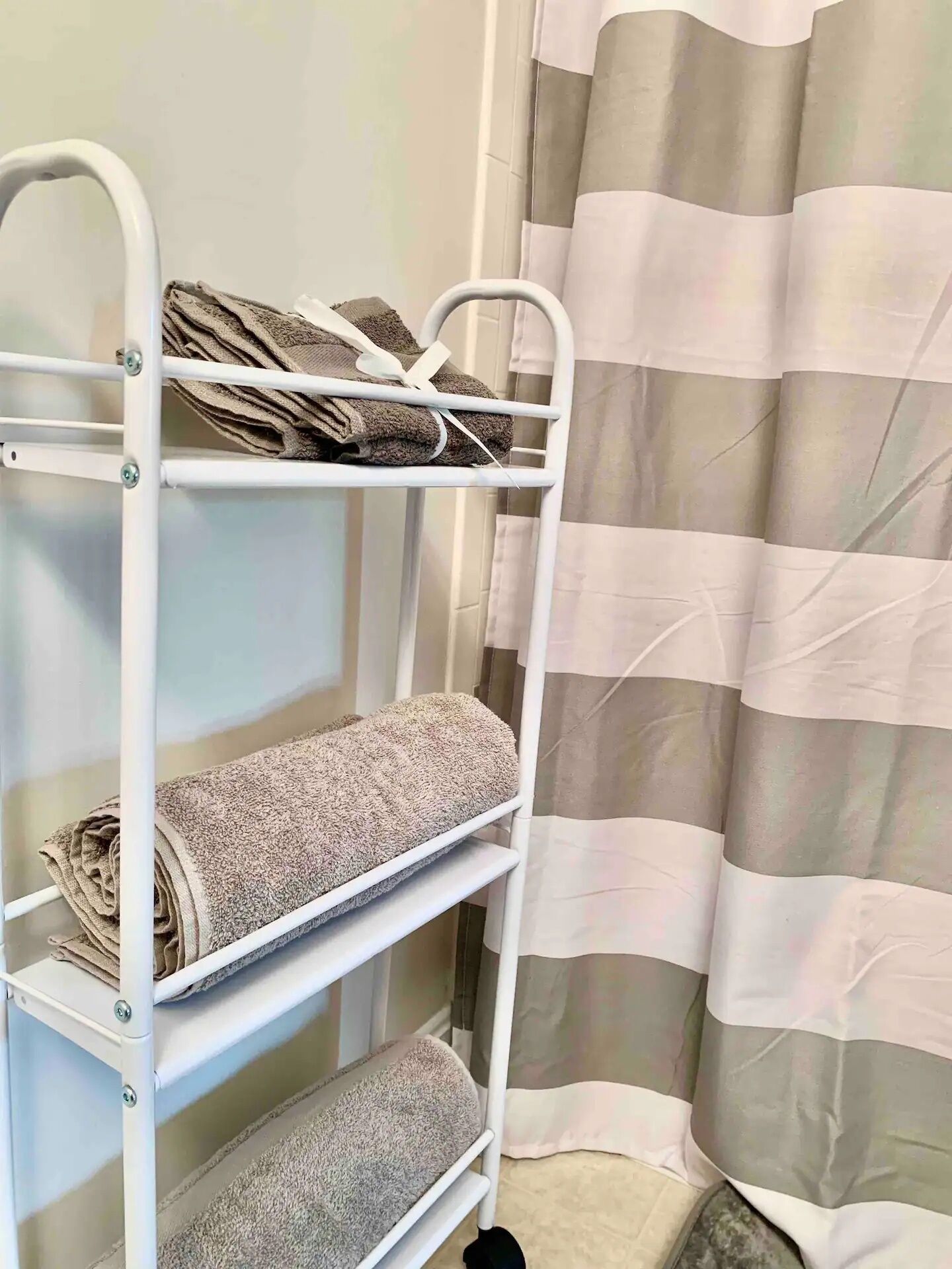 Una cama litera de metal blanco con toallas en cada repisa.