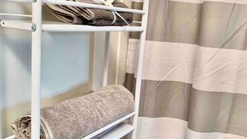 Una cama litera de metal blanco con toallas en cada repisa.