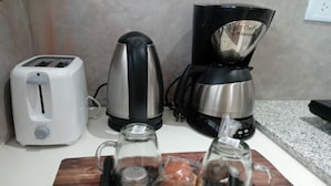 A kitchen counter with a toaster, a kettle, and a tray with salt, pepper, and a lemon. - Consorcio General Acha ,apartamentos (San Juan)
