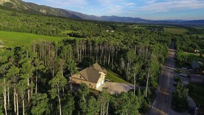 Una casa circondata da un bosco fitto, con una strada ben visibile nelle vicinanze.